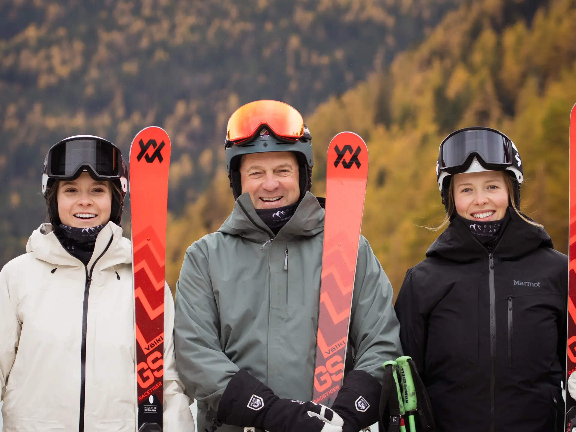 Smiling skiers with equipment in front of autumn forest | © J.K.