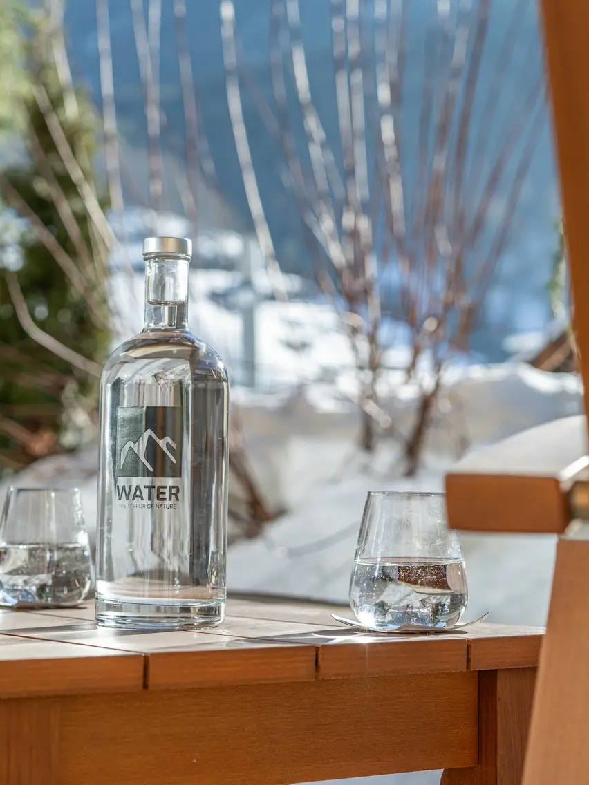 Water bottle and glasses on wooden table in front of winter landscape | © Johannes Brunner